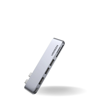 A silver aluminum USB-C hub with multiple ports, branded with 'UGREEN' on its side, shown floating against a solid white background with a soft shadow underneath.